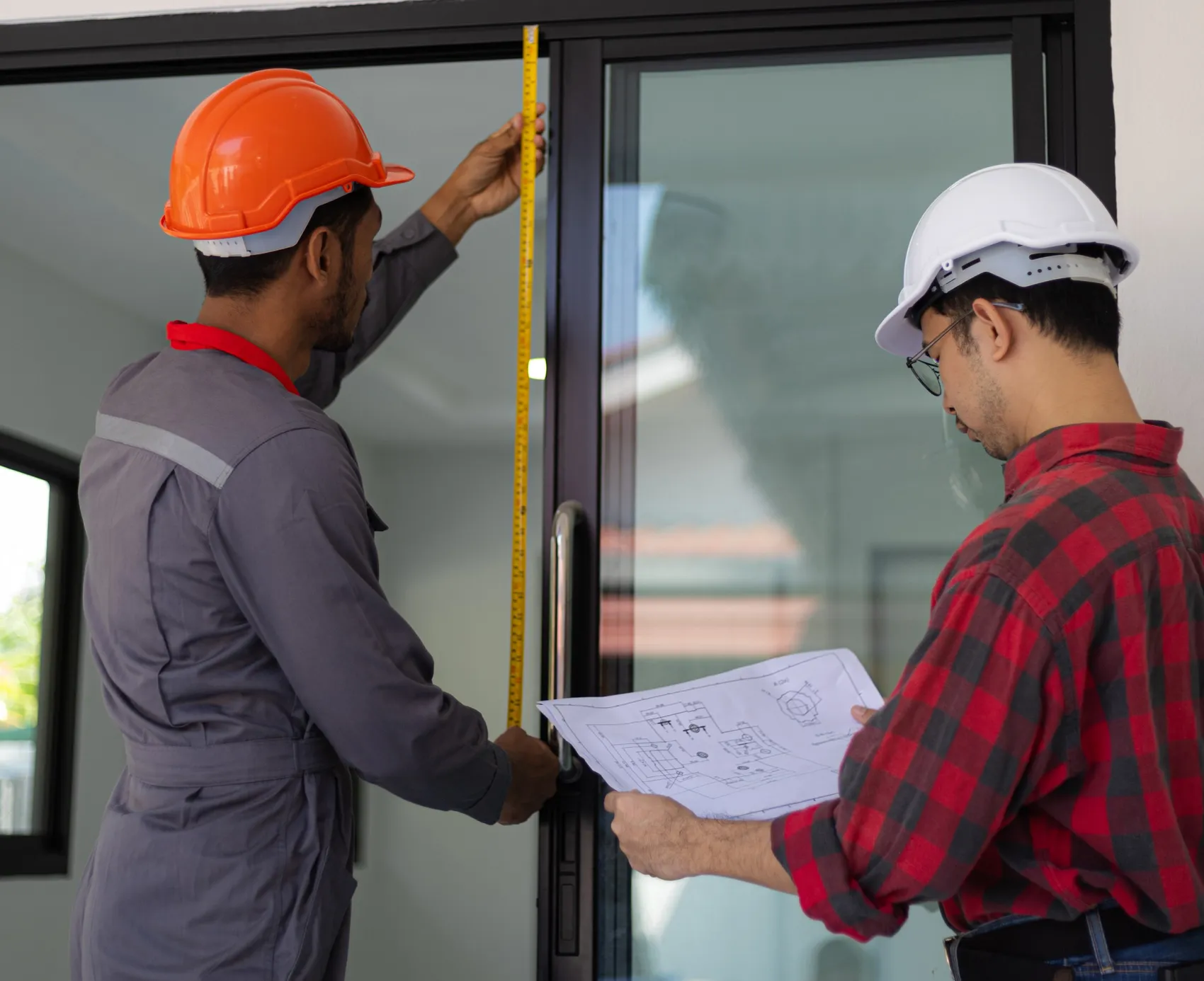 Worker in a hard hat measuring a window opening